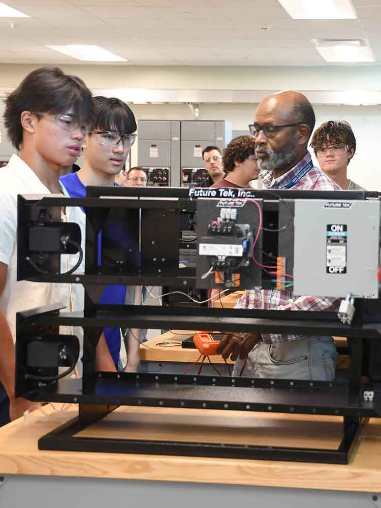 electrical tech students watching their professor demonstrate an electrical fix