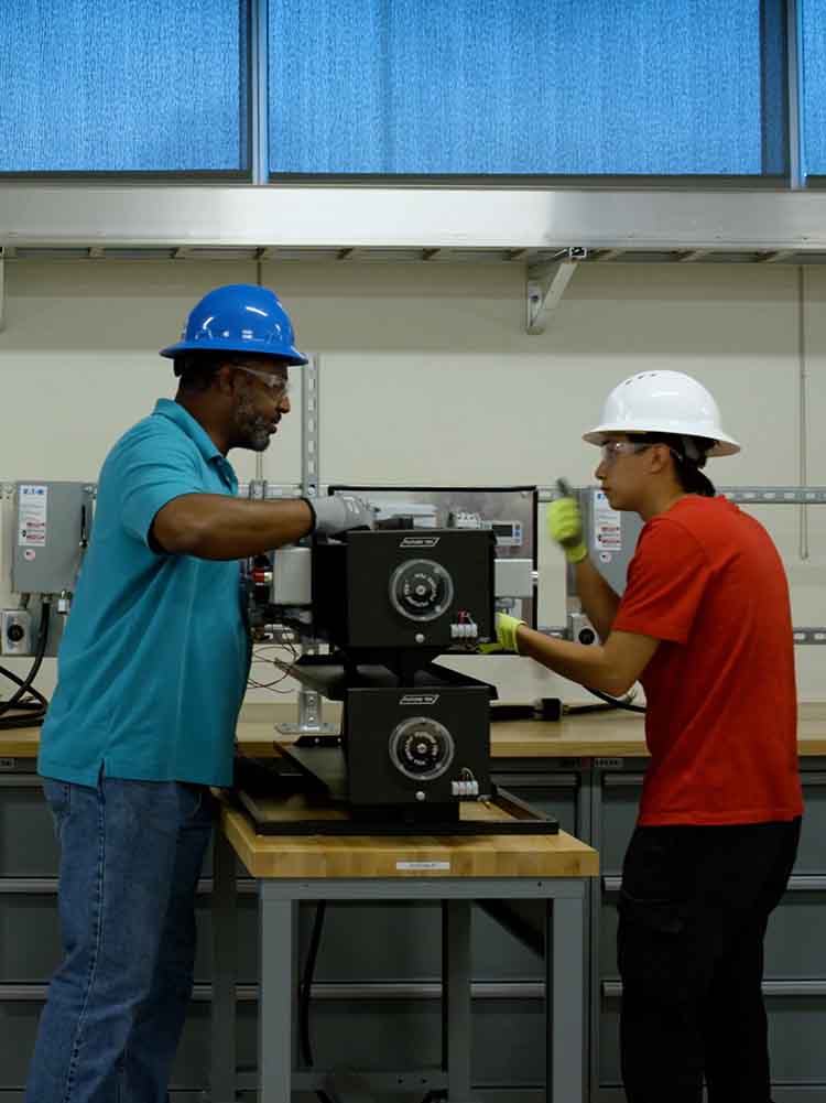 electrical tech professor showing a student how to operated on an electrical project