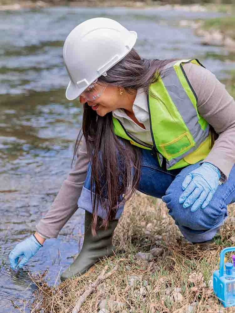 environmental health and safety worker taking a sample from river